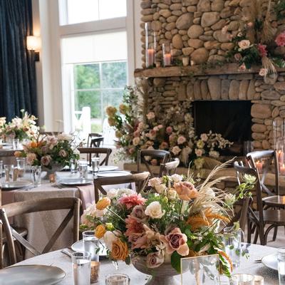 Elegant dining room with rustic stone fireplace, adorned with lush floral arrangements