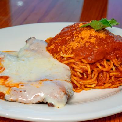 Chicken parmigiana served alongside spaghetti and basil.