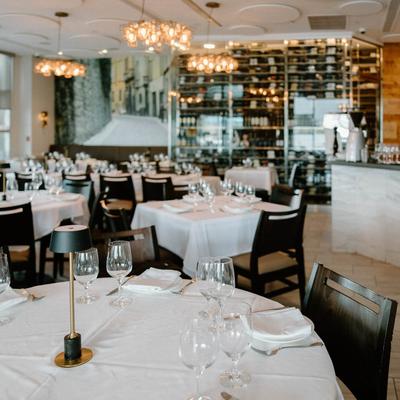 Elegant restaurant interior with set tables, wine glasses, and chandeliers.