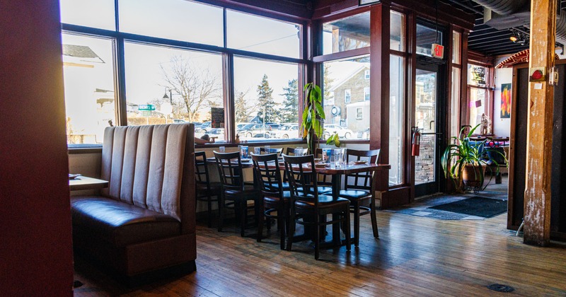 Interior with large windows, tables with glasses and wooden chairs.
