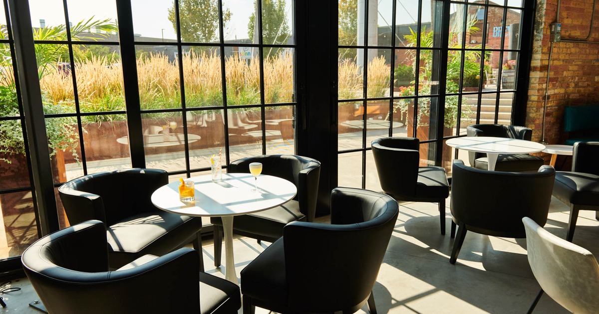 Lounge seating with round tables by large industrial windows