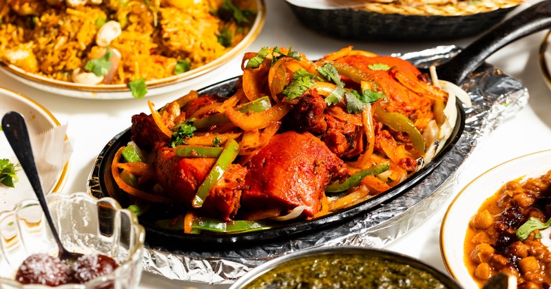 Sizzling chicken platter with peppers and onions on a hot skillet