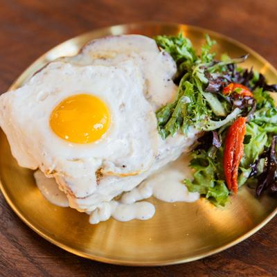 Croque Madame sandwich topped with fried egg and served with a side salad.