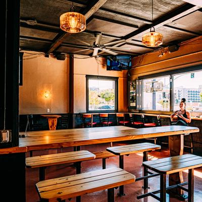 Interior with wooden communal tables, benches and industrial-style lighting.