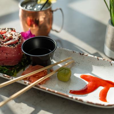 A white platter holds tuna sashimi, seaweed, ginger, wasabi, sauce, and chopsticks.
