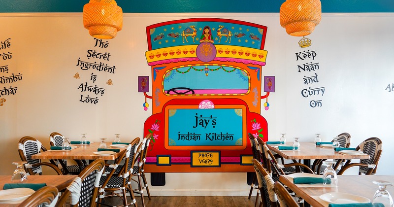 Interior space, dining room with set tables, Indian bus drawing on the wall