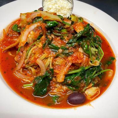 Mediterranean calamari stew featuring sauteed spinach and olives.