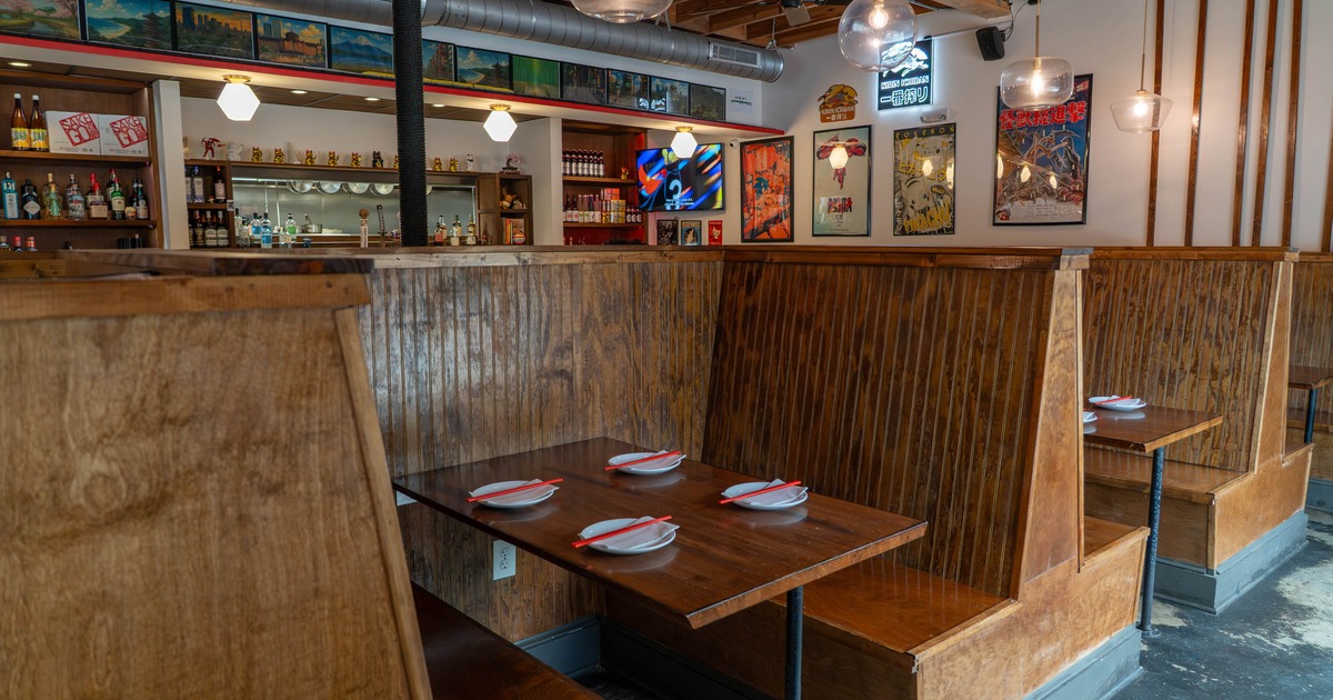 Interior of a restaurant with wooden booths, set tables with plates and chopsticks