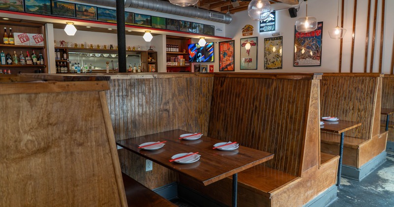 Interior of a restaurant with wooden booths, set tables with plates and chopsticks