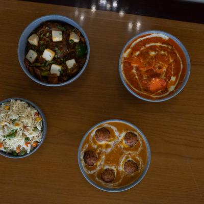 Assorted curry bowls on the table alongside a bowl of rice.
