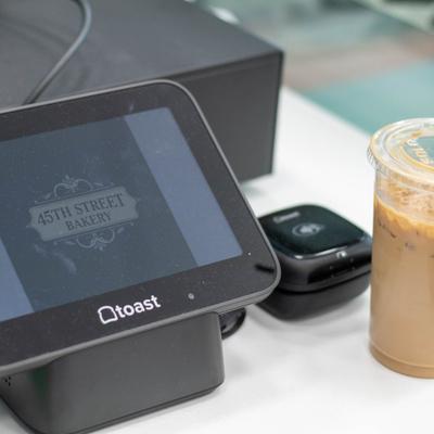 POS terminal and card reader setup on a counter next to an iced beverage.