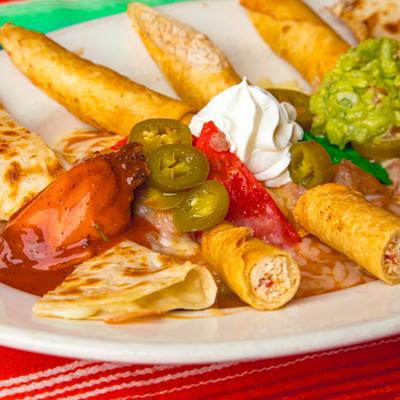 Mexican appetizer platter with taquitos, quesadilla wedges, guacamole, and jalapenos.