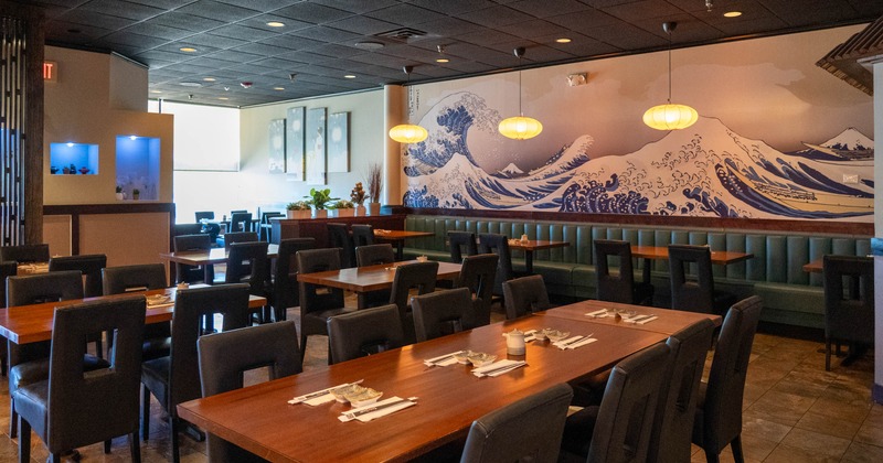 A Japanese-themed restaurant with wooden tables and wave mural