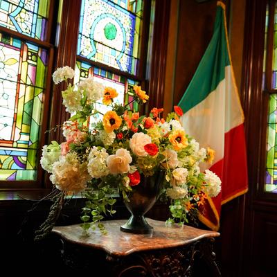 Interior, floral display on a table with Italian flag.