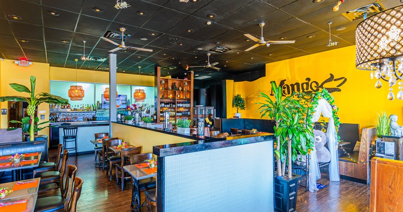 A colorful interior with tables, chairs and orange walls.
