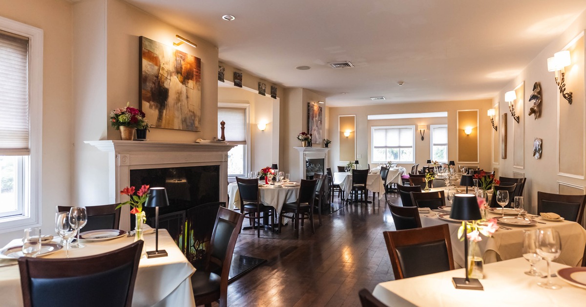 Interior dining area with tables set with white tablecloths, and a fireplace
