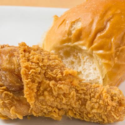 Fried chicken leg and bread roll.
