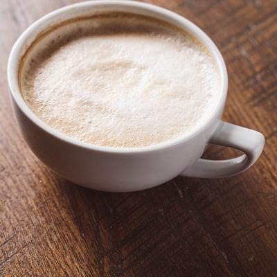 A cup of frothy latte on a wooden table