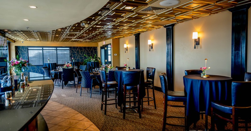 Elegant dining area - a bar, round tables, dark leather chairs and golden ceiling patterns