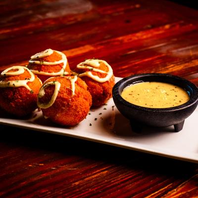 Mac and cheese balls stuffed with brisket, served with a cup of Alabama white BBQ sauce.