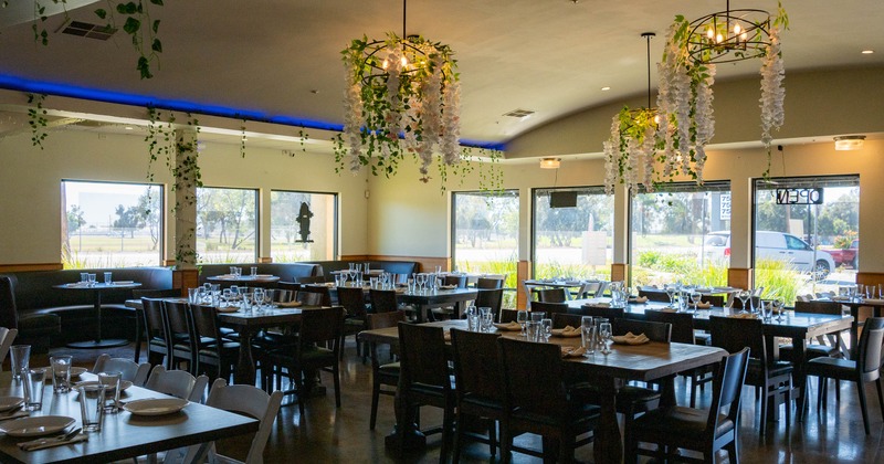 Interior  with tables set for service, featuring floral chandeliers and large windows
