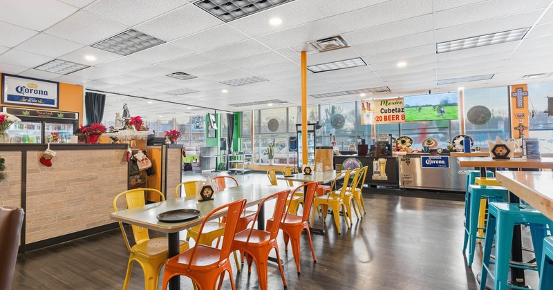 Colorful casual interior with yellow and orange chairs, bright décor and a sports event on TV