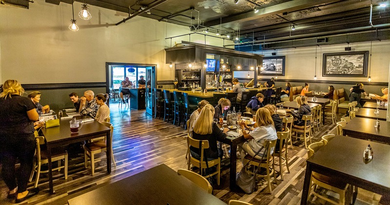 Interior, dining area around a bar, with guests dining and wait staff working
