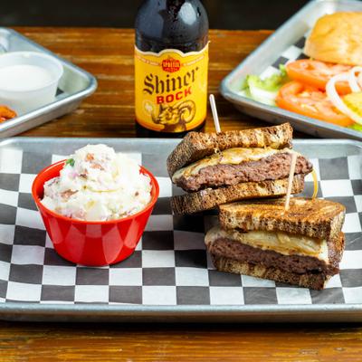Patty melt served with coleslaw, alongside a bottle of beer.