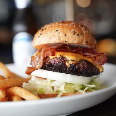 Baco cheeseburger served on a plate with fries on the side, close-up.