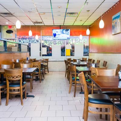 Restaurant dining room with tables and chairs, booths and front windows.