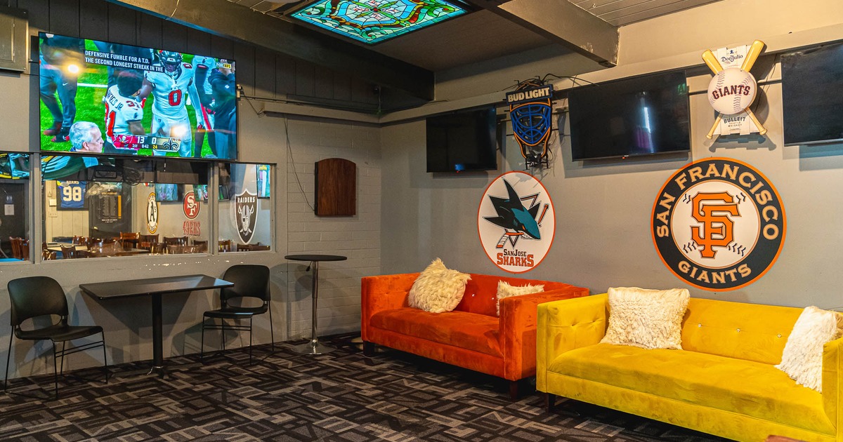 Interior, sofas, tables and chairs near wall with logos and TVs