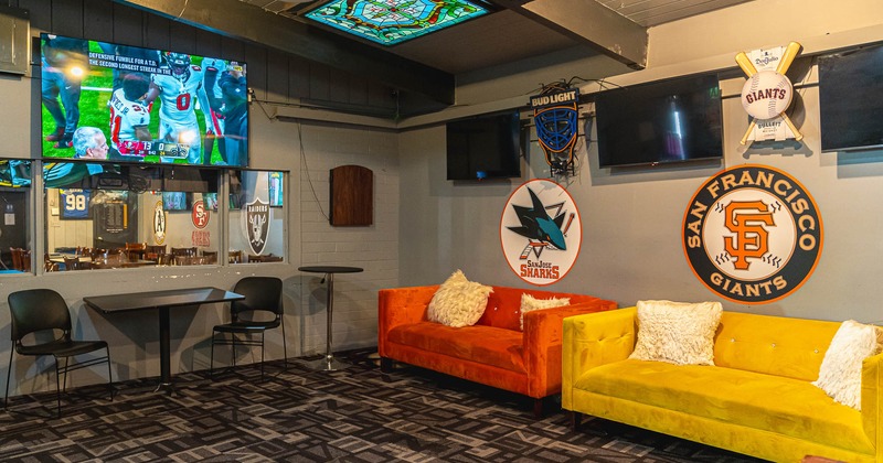 Interior, sofas, tables and chairs near wall with logos and TVs