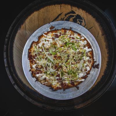 Pizza featuring a thin crust topped with meat, white sauce and shredded lettuce.