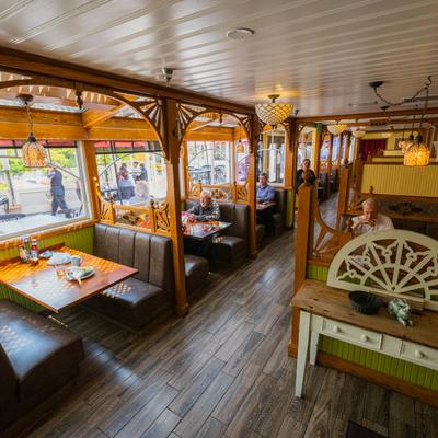 Cozy restaurant interior with wooden booths, People sit at tables near large windows.