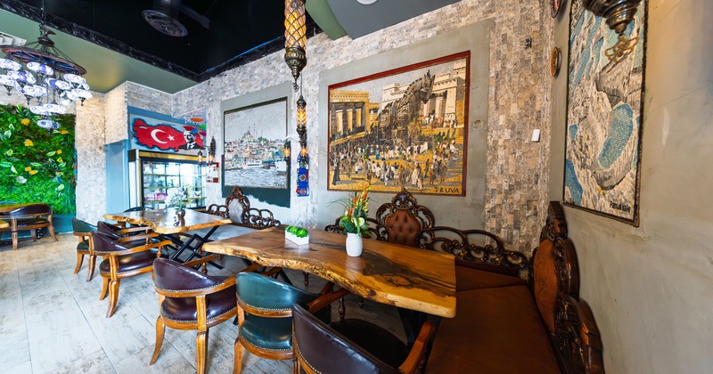 Seating area with vintage-style booth seats along the walls, dark leather chairs, and wooden tables