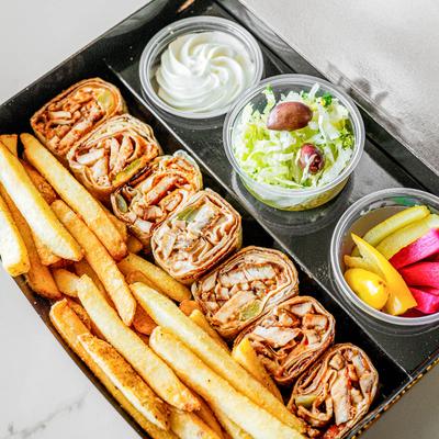 A take out box with chicken shawarma, veggies, sauce, and fries.