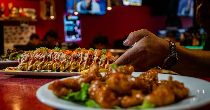 A plate of a colorful sushi roll is placed on a counter with pan-fried chicken plate