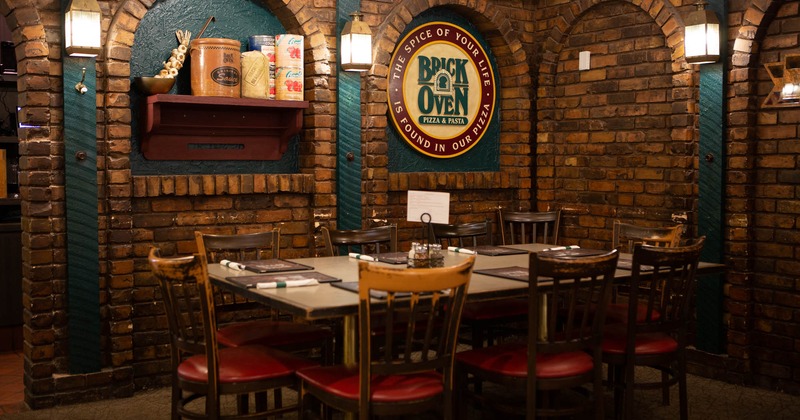 Interior, table, and chairs with tableware, brick wall in the back