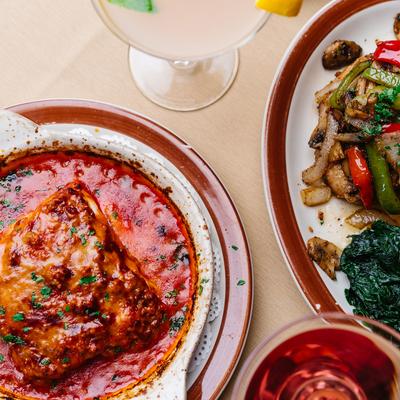 Lasagna, pork chop, and two drinks, top view.