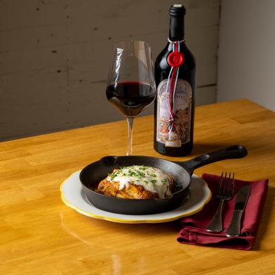 Lasagna served with a glass of red wine on a wooden table.