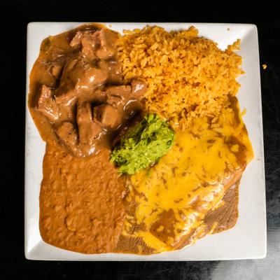 Texas plate featuring carne guisada, a cheese enchilada, rice, beans and guacamole.
