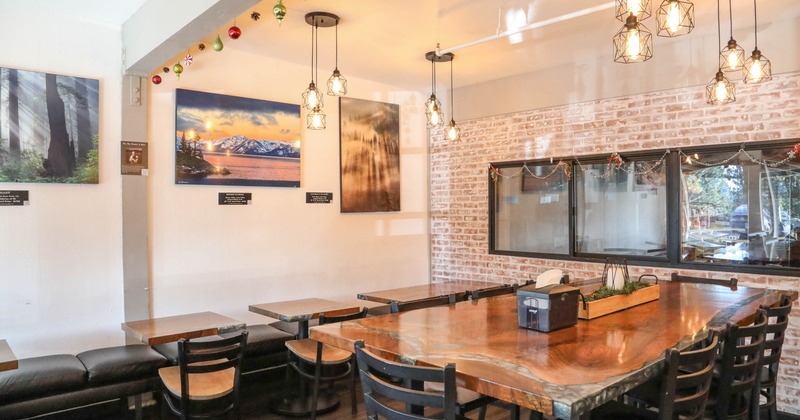 Cozy dining area with pendant lights, a large wooden table, landscape photographs
