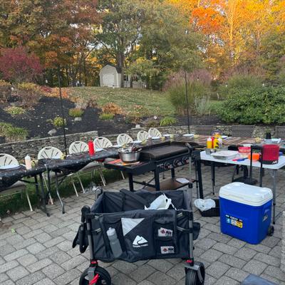Outdoor patio with a coking setup and tables surrounded by fall trees.