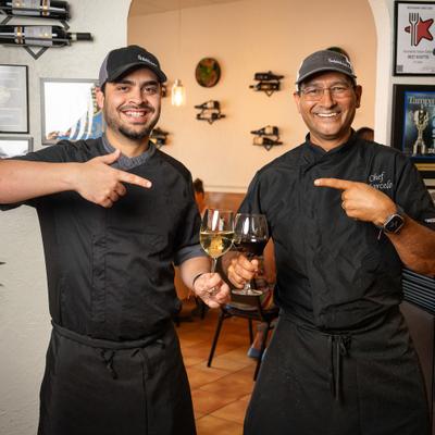 Two individuals wearing black chef uniforms and hats.