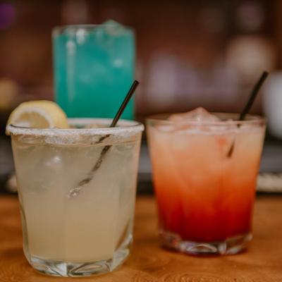 Three different cocktails served on a wooden bar counter.