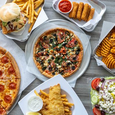 Food spread with pizzas, fries, mozzarella sticks, fish, and salad.