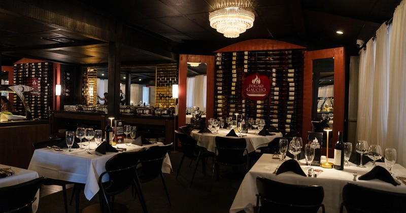 Dimly lit interior - white-tablecloth tables,  a crystal chandelier, wall-mounted wine racks.