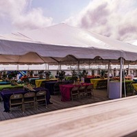 A spacious tent with neatly arranged tables and chairs on the deck.