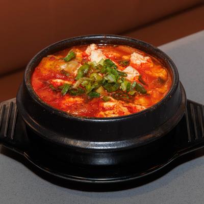 Soft tofu stew topped with chopped scallions.