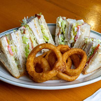 Double Decker Clubhouse sandwich served with onion rings.